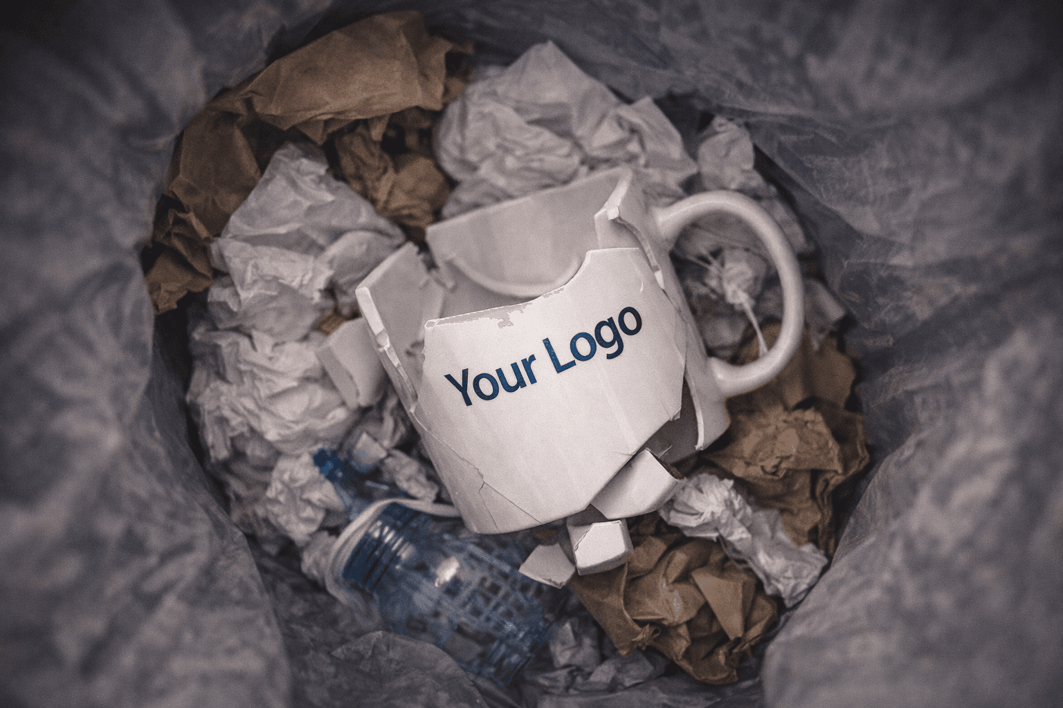 Broken branded corporate mug in trash